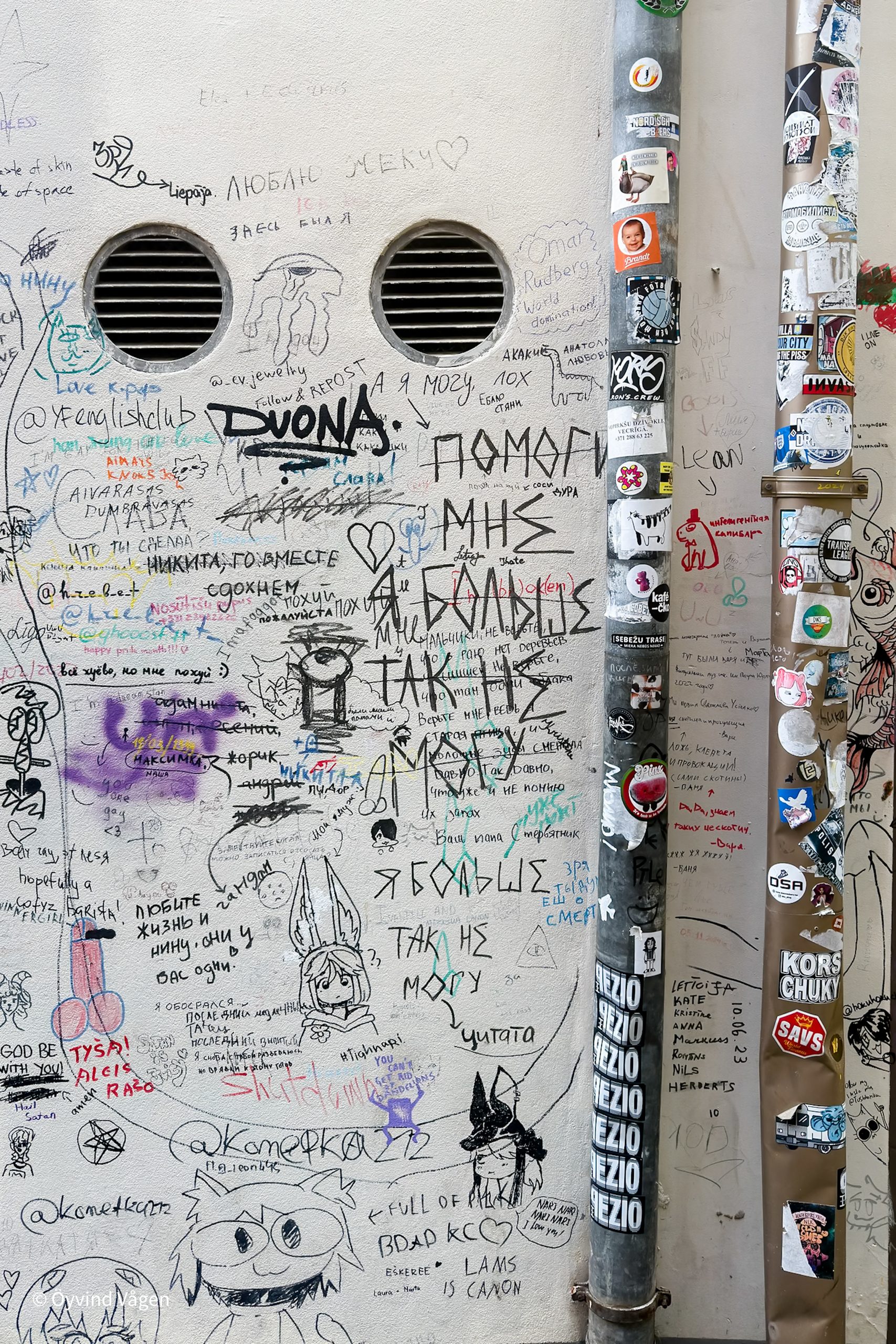 Vägg med klistermärken och graffiti.