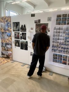 En besökare betraktar fotografier och bildserier på en utställningsvägg.