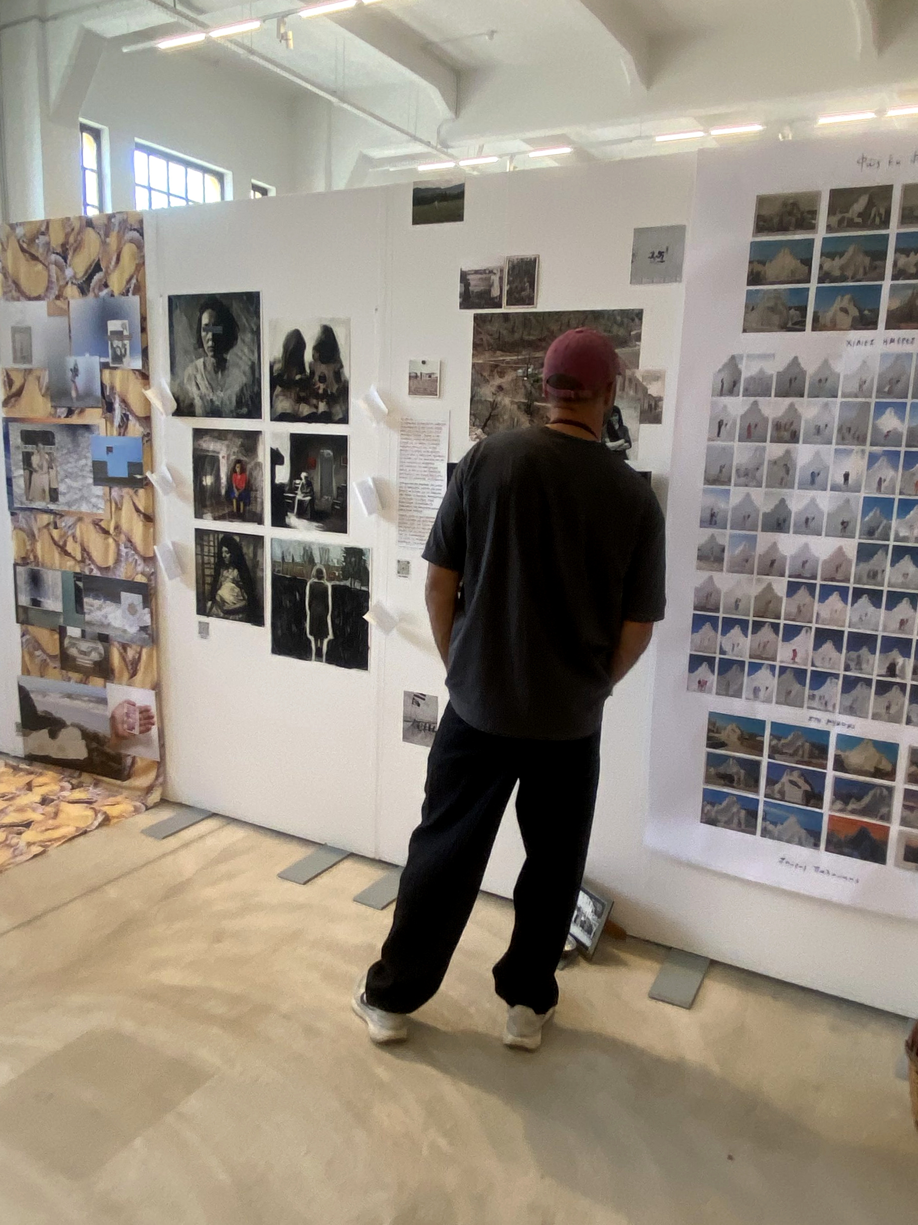En besökare betraktar fotografier och bildserier på en utställningsvägg.