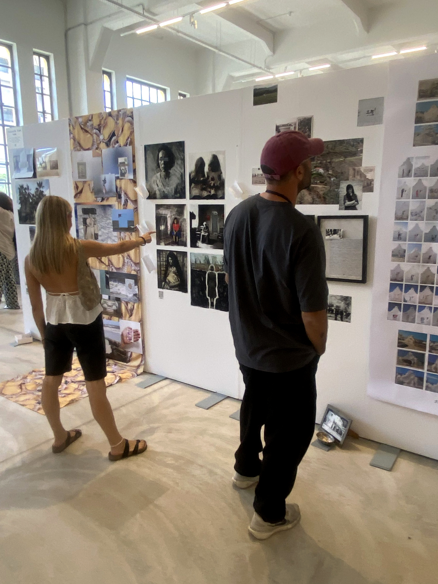 Två besökare betraktar fotografier; en av dem pekar mot ett verk.