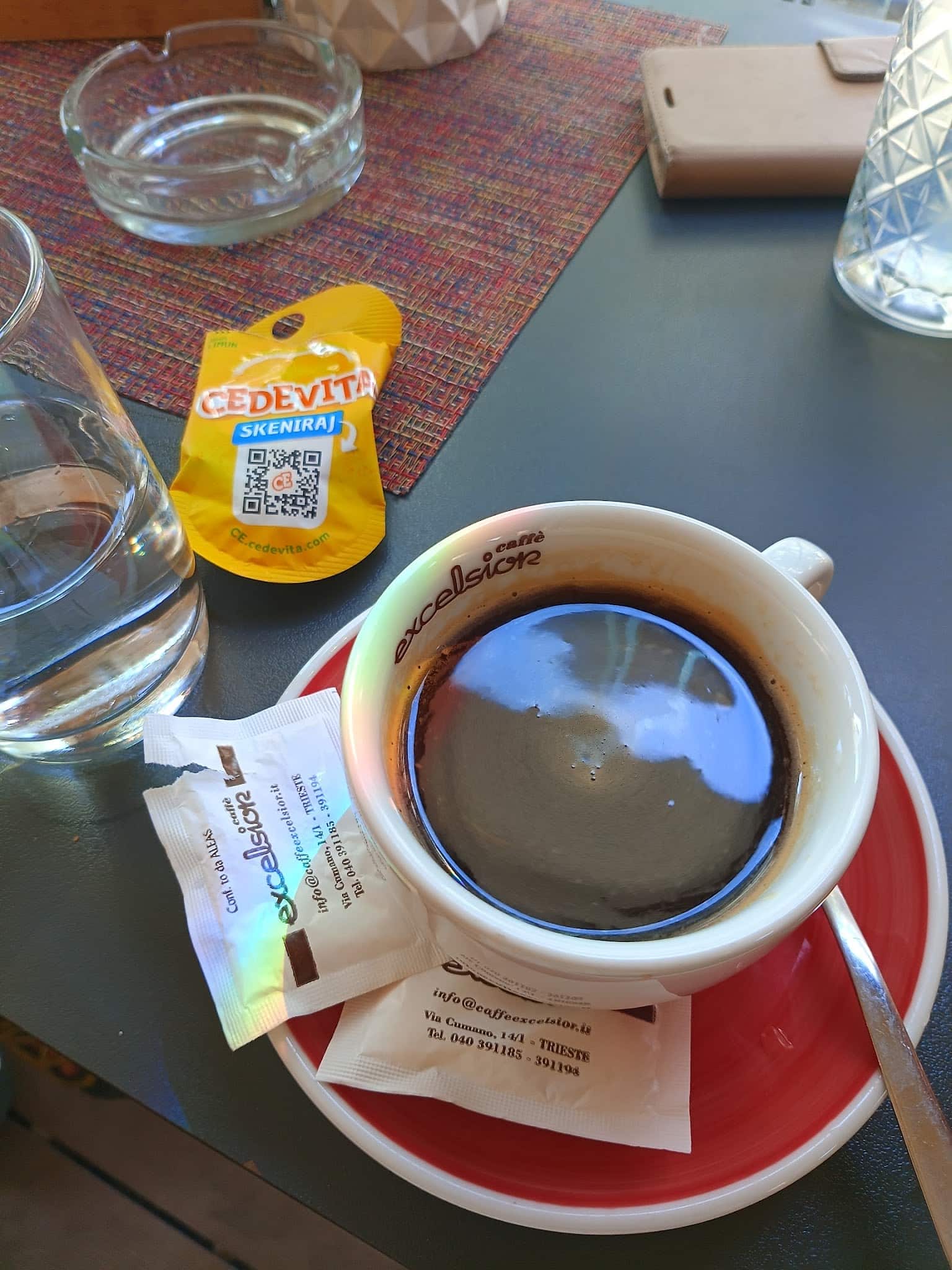 A cup of coffee with a glass of water at a café table