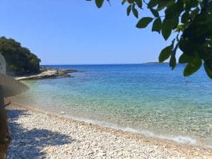 A pebble beach beside clear turquoise water
